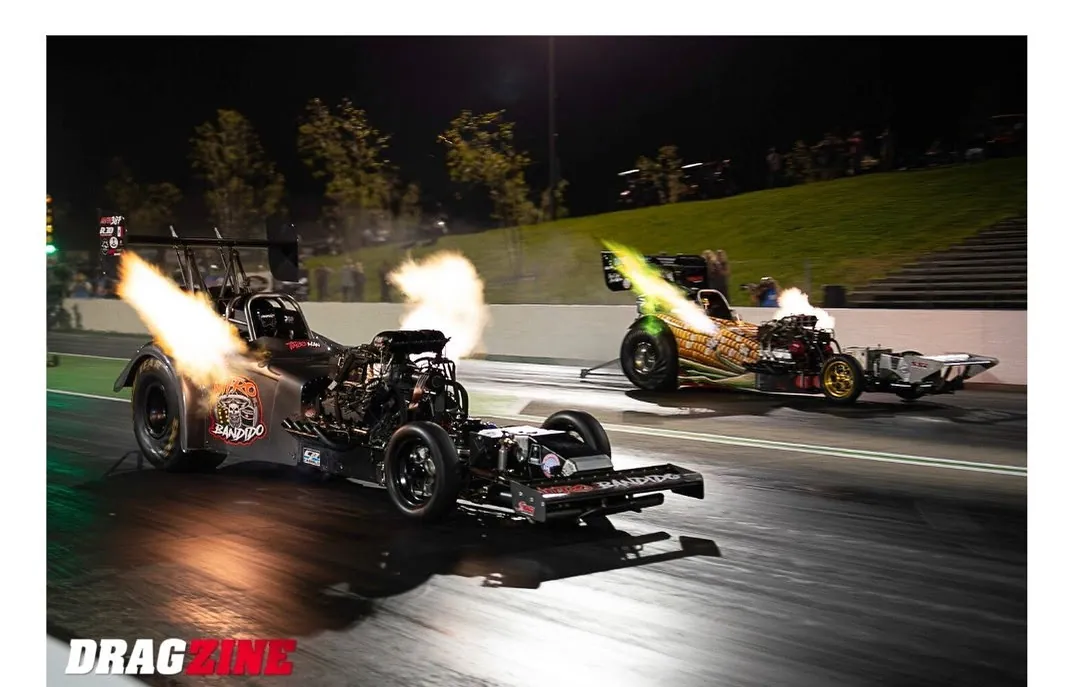 Pete Dove's corn car and Ryan Hill's Nitro Bandido side by side at night with header flames