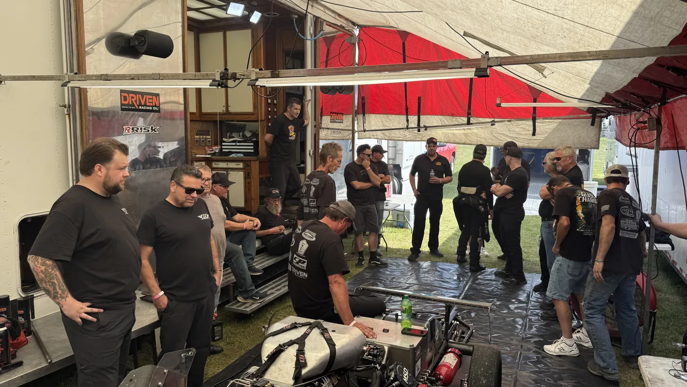 People gathered in a nitro pit, watching the crew work on a Fuel Altered